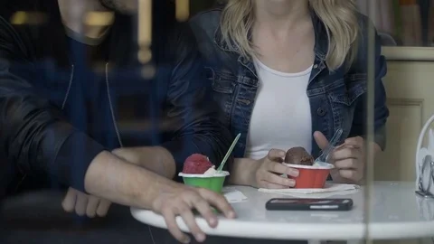 Teenage couple enjoying their first date talking and eating ice cream into a Stock Footage