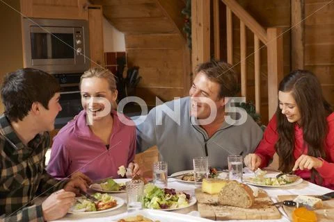 Teenage Family Enjoying Meal In Alpine Chalet Together Stock Photos