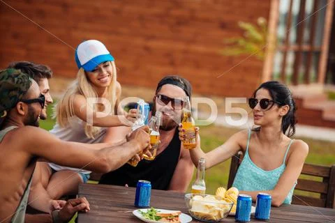 Teenage Friends Sitting At Table And Having Fun Outdoors