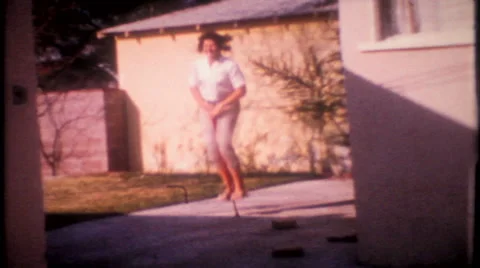 Teenage girl on pogo stick in the driveway 1950s vintage film home movie 2771 Stock Footage