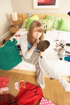 Teenage Girl Putting On Make Up In Untidy Bedroom Stock Photos