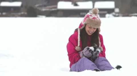 Teenage girl sits in snow as brother creeps up behind her before dropping snow Stock Footage