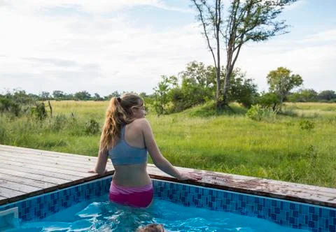A teenage girl in a swimming pool looking out at the landscape around a safari Stock Photos