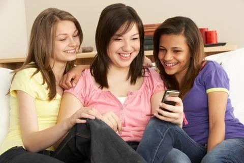 Teenage Girlfriends Reading Mobile Phone at Home Stock Photos
