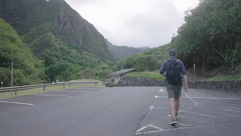 Teenage Hiker walks through empty parking lot in Iao Valley Maui Hawaii. Stock Footage 141796053