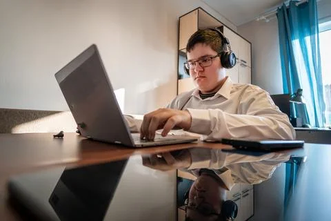 Teenage man studying using computer, headphones, smartphone for online clas.. 写真素材