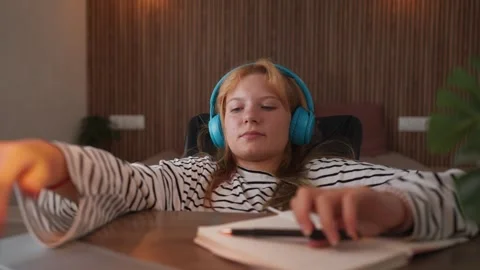 Teenage student distracted from homework while listening to music through h.. Video stock 345152709
