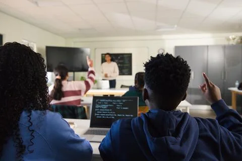 Teenage students studying coding with teacher student raising hand near laptop Stock Photos