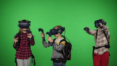 Teenage use VR headset helmets to play an imitation game on a green background. Stock Footage 317001058