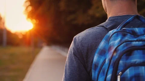 A teenager with a backpack is walking along the road to school, only his Stock Footage