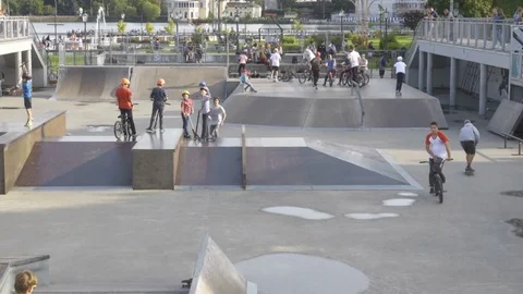 Teenager biker at skate park. Skateboarder doing a trick in a skatepark. Teen Stock Footage