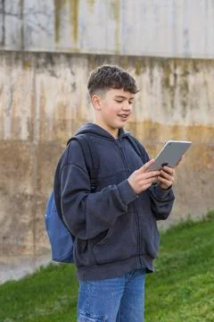 Teenager boy with backpack using digital tablet outdoors Stock Photos