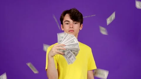 Teenager boy looking at camera while banknotes flying Stock Footage 248954308