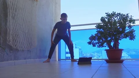 Teenager boy with tablet computer doing sport exercises on balcony. Sport Stock-Footage 130662637