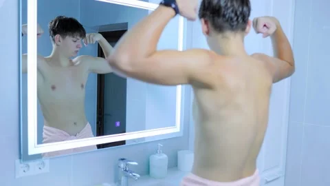 Teenager checking flexed biceps muscles reflecting modern bathroom mirror. Stock Footage 345531694