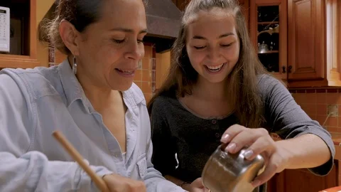 Teenager daughter using a cell phone to help her Mexican mother bake Stock Footage
