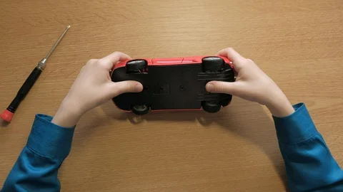 Teenager disassembling his red model supercar. Use screwdriver to unscrew cogs Stock Footage 129402724