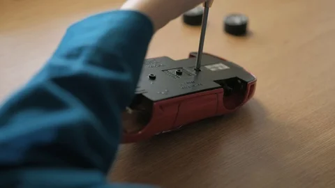 Teenager disassembling his red model supercar. Use screwdriver to unscrew cogs Stock Footage 129402770