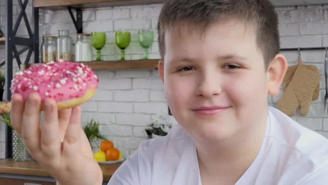 Teenager eats junk food while working at home. Attractive plump handsome young Stock Footage 233381133