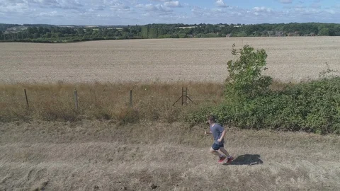 Teenager Jogging From The Side Using a Drone In UK Countryside Stock Footage 93485261