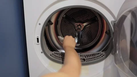 Teenager loading clean laundry into clothes dryer for home chores Stock Footage 320182908