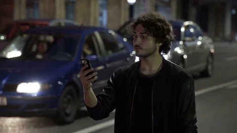 Teenager man waiting and checking smartphone in the night for Uber car order Stock Footage