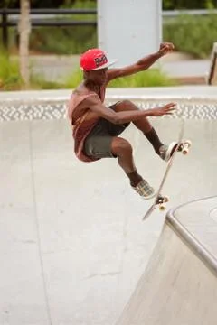 Teenager performs jump while practicing skateboarding at skateboard park Stock Photos