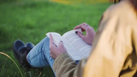 Teenager reading a book at a meadow Stock Footage