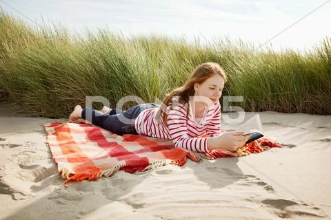 Teenager Reading Book In Sand Dunes