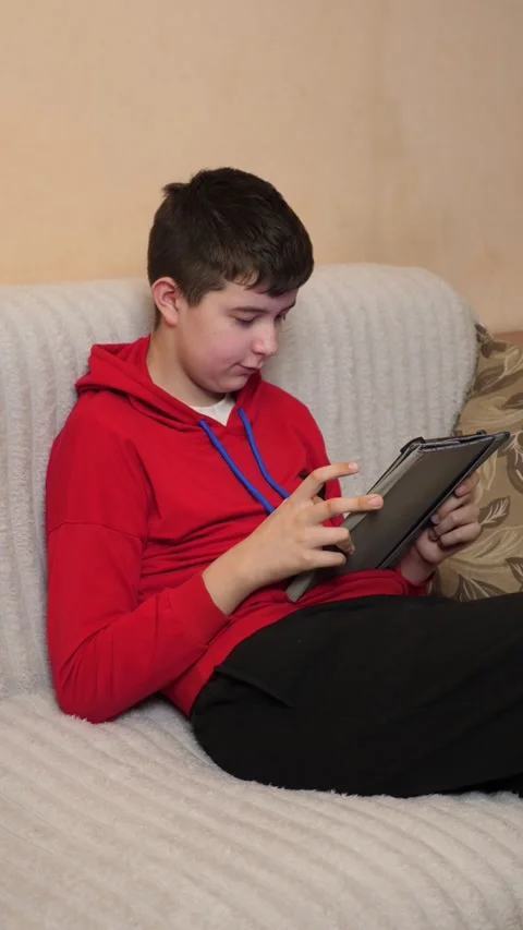 A teenager uses a tablet while sitting on a couch. Video stock 313729441