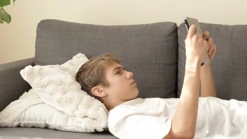 Teenager using digital tablet computer at home. Boy playing video racing game on Stock Footage 221758863