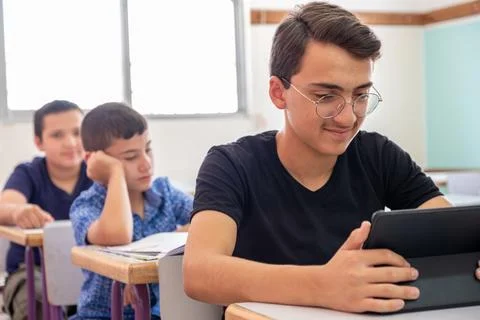 Teenager using the tablet in school and have a smile on his face Stock Photos
