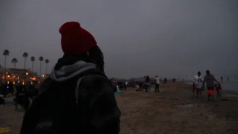 Teenager walks down crowded beach Stock Footage 80579956