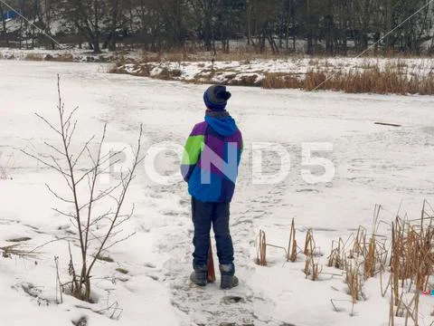 Teenager in winter goes to the ice of the lake. danger. Stock Photos