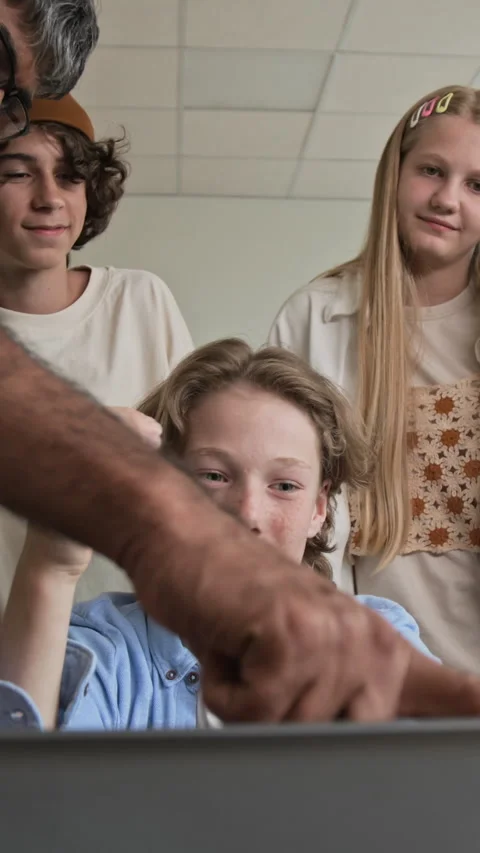Teenagers Collaborating on Laptop Computer with Teacher in Classroom Stock Footage 342825713