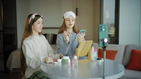 Teenagers engage in makeup tutorial at home table during daylight while recordin Stock Footage 337638324