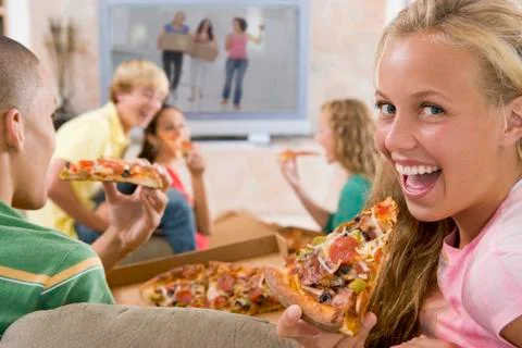 Teenagers hanging out in front of television eating pizza Stock Photos