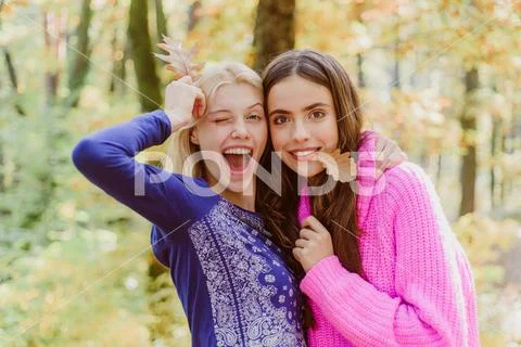 Teenagers having fun on autumn background. Two Surprise woman playing with Stock Photos