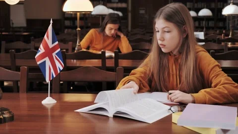 Teenagers in the library preparing for lessons background of Great Britain flag. Video stock 150866493