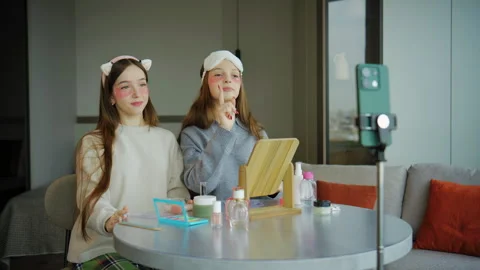 Teenagers prepare for a makeup tutorial video in a well-lit room during the afte Stock Footage 337640880