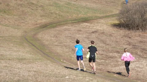 Teenagers running along a country road through a spring field Stock Footage