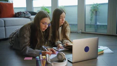 Teenagers study and do homework together on the floor in a living room during th Stock Footage 337856717