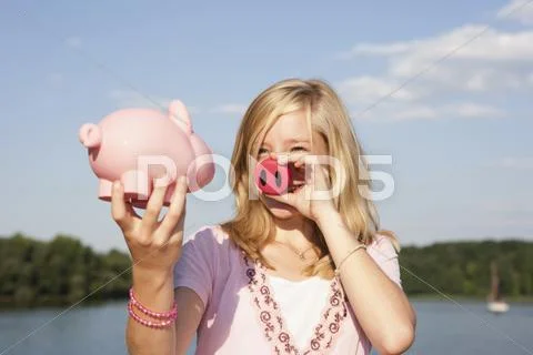 A teengirl holding a pig nose and a piggy bank Stock Photos