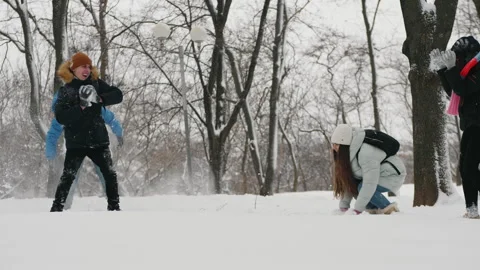 Teens ave fun throwing snow at each other in city park Stock Footage 146965556