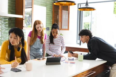Teens collaborating on school project using tablet and smartphones in modern Stock Photos