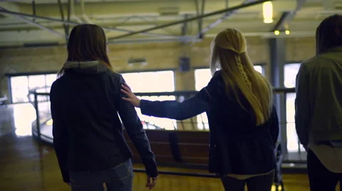 Teens Find A Bench To Sit On Inside, Girl Puts Her Arm Around Friend As They Sit Vídeos de archivo 63384793