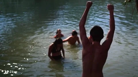 Teens Getting Out Of Water, Their Friend Cheers Them On From The Riverbank Video stock 47493522