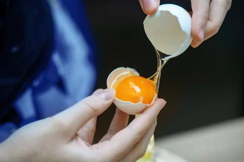 Teens hands separating egg yolk from white using an innovative eggshell Stock Photos