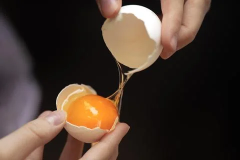 Teens hands separating egg yolk from white eggshell. Stock Photos