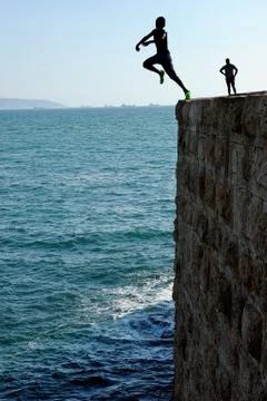 Teens, jumping into the sea. Stock Photos